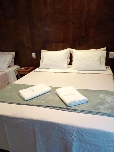 two white towels are sitting on a bed at Chalés Vista dos Carvalhos in Capitólio