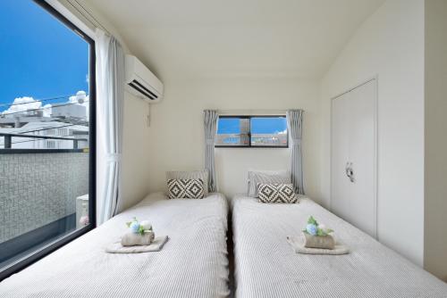 two beds in a room with a large window at Aiki No Yado-Kokuba- in Naha