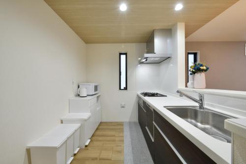 a white kitchen with a sink and a stove at Aiki No Yado-Kokuba- in Naha
