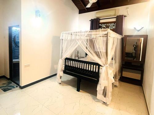 a bedroom with a bench with a canopy in a room at Lunara Sanctuary in Induruwa
