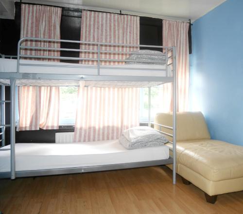 a bedroom with bunk beds with a couch and a chair at Kensal Green Backpackers 2 in London
