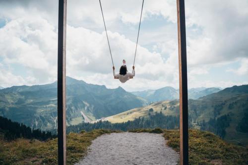 a person on a swing over a river in the mountains at Boutique Hotel Hohes Licht in Damuls