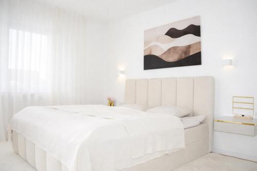 a white bedroom with a white bed and a painting at Ferienwohnung Südwind 3 in Küssaberg