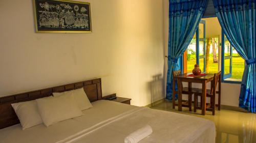 a bedroom with a bed and a table and a window at serenity Lake Resort yala in Tissamaharama