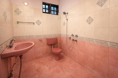 a bathroom with a pink toilet and a sink at Heritage Inn in Lucknow