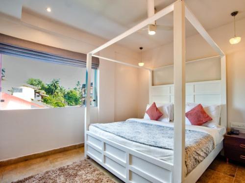 a bedroom with a canopy bed and a large window at Hotel Pajaros Blu in Calangute