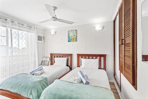two twin beds in a room with a window at Capricorn Whitsunday in Cannonvale