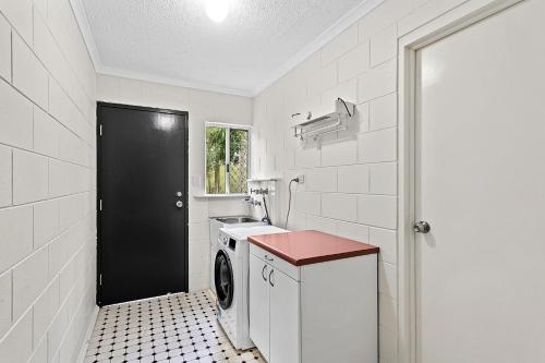 a kitchen with a washing machine and a black door at Capricorn Whitsunday in Cannonvale
