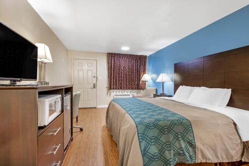 a hotel room with a bed and a flat screen tv at Econo Lodge Woodstock - Shenandoah Valley I-81 in Woodstock