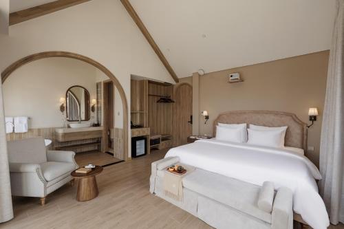 a bedroom with a large white bed and a chair at Là Thông Boutique Đà Lạt in Da Lat