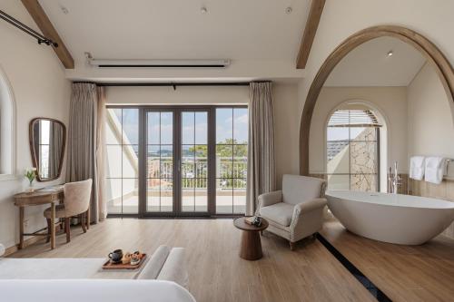 a large bathroom with a large tub and a chair at Là Thông Boutique Đà Lạt in Da Lat
