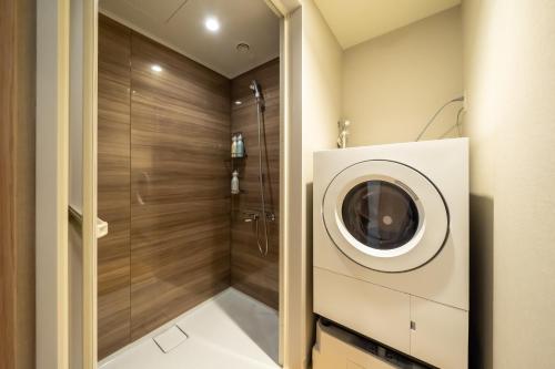 a bathroom with a shower and a washing machine at Hotel Monterey La Soeur Naha in Naha