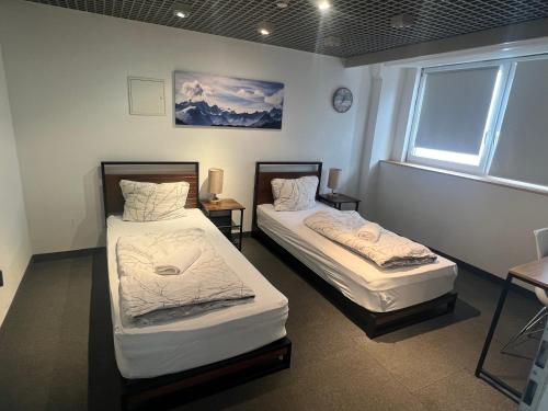 two beds in a room with a window at Work & Stay KemptenCityHost in Kempten