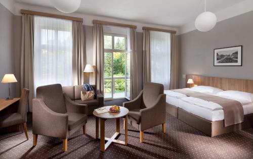 フランチシュコヴィ・ラーズニェにあるBadenia Hotel Prahaのベッド、テーブル、椅子が備わるホテルルームです。