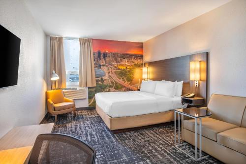 a hotel room with a large bed and a couch at Clarion Pointe in Winnipeg