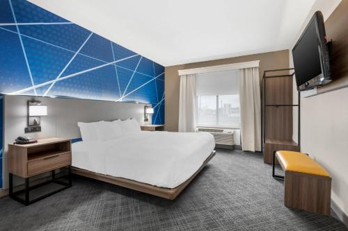 a hotel room with a bed and a flat screen tv at Comfort Suites Fort Wayne North in Fort Wayne