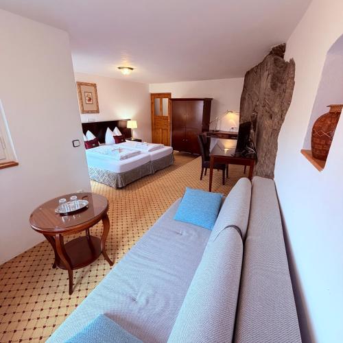 a hotel room with a couch and a bed and a table at Penzion Kapr in Český Krumlov