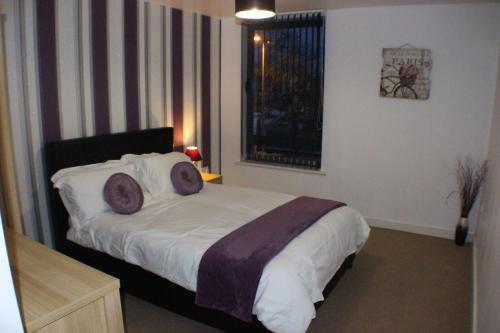 a bedroom with a bed with purple pillows and a window at Marina Water View Apartment in Hull
