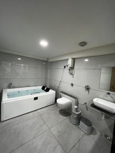 a bathroom with a tub and a toilet and a sink at Hotel Krishna Palace in Pālanpur