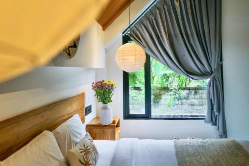 a bedroom with a bed and a window at Dzen Greenfield Villa 6 in Ubud
