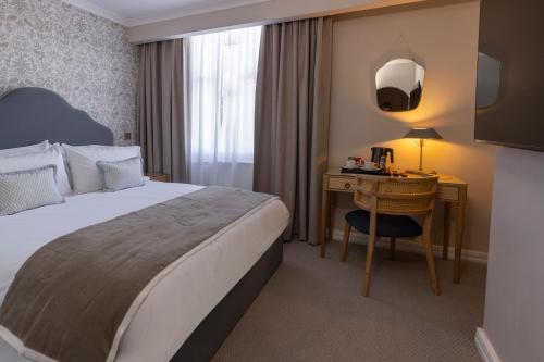 a hotel room with a bed and a desk at Newton Park Country House Hotel in Burton upon Trent
