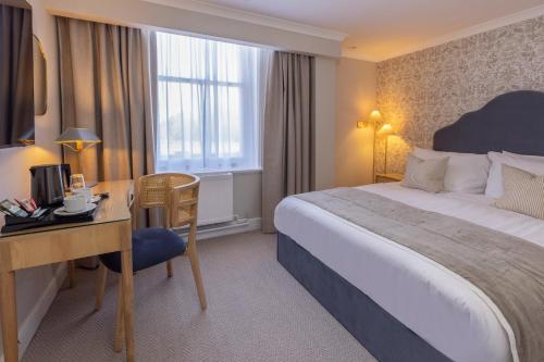 a hotel room with a bed and a desk and a bed and a desk at Newton Park Country House Hotel in Burton upon Trent