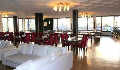 ガルミッシュ・パルテンキルヒェンにあるホテル アトラス シュポルトの白いソファ、テーブル、窓のあるレストラン