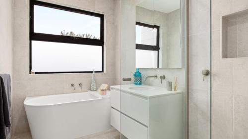 a white bathroom with a tub and a sink at Fleetwood Atelier in Frankston South