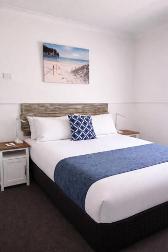 a bedroom with a large bed with a blue and white blanket at Busselton Jetty Chalets in Busselton