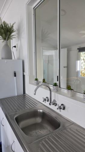 a kitchen with a sink and a mirror at Busselton Jetty Chalets in Busselton