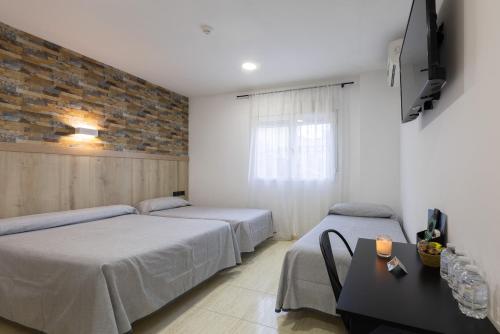 a bedroom with two beds and a tv on a wall at Hostal 82 in Olías del Rey