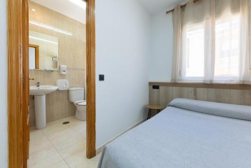 a bedroom with a bed and a sink and a toilet at Hostal 82 in Olías del Rey