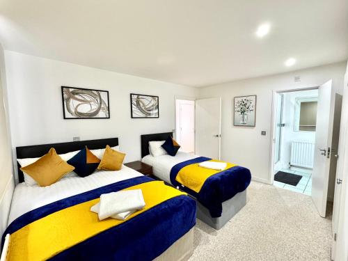 a bedroom with two beds with yellow and blue at 2 Bed, 2 Bath, Ground Floor Whole Apartment with Parking, Near Central London & Stratford, Close to Station, Zone 2 in London