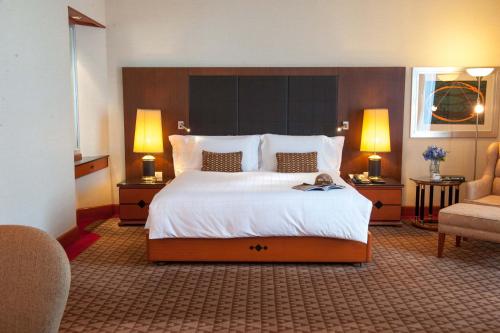 a large bed in a hotel room with two lamps at The Heritage Grand Khon Kaen Hotel and Convention in Khon Kaen