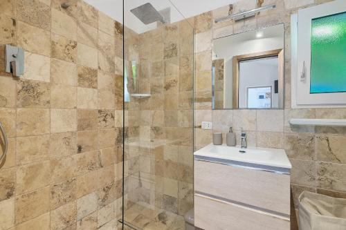 a bathroom with a shower with a sink and a mirror at Casa Kim - Capoliveri in Capoliveri