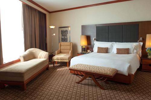 a hotel room with a large bed and a chair at The Heritage Grand Khon Kaen Hotel and Convention in Khon Kaen