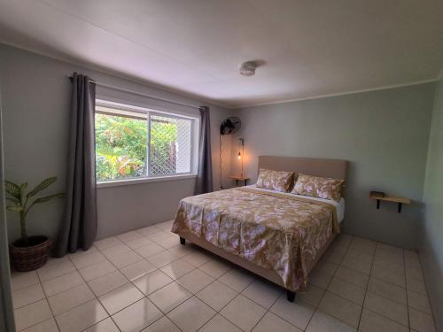 a bedroom with a bed and a large window at Akaroa Hideaway in Avarua