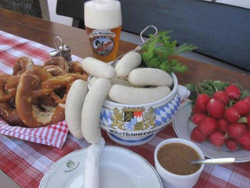 a table with a bowl of hot dogs and a beer at Gasthof Hinterwirt in Übersee