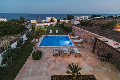 a swimming pool with tables and chairs and the ocean at Deep Blue Villa in Lachania
