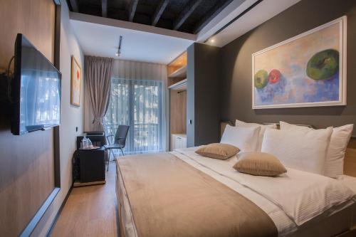 a bedroom with a bed with two pillows and a television at Solun's Riverside Rooms in Skopje