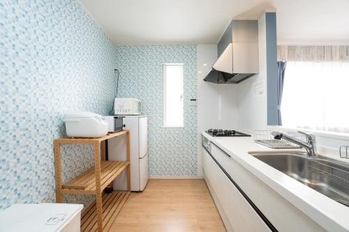 a kitchen with a sink and a refrigerator at 古宇利島まで車で10分の星降るやんばるテラス海まで徒歩3分のは1棟貸 in Nago