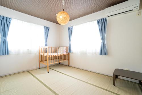a baby room with blue curtains and a crib at 古宇利島まで車で10分の星降るやんばるテラス海まで徒歩3分のは1棟貸 in Nago