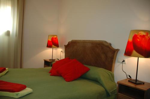 um quarto com uma cama com almofadas vermelhas e 2 candeeiros em Cal Marroso em Montsonis