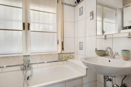 a white bathroom with a sink and a bath tub at Casa Braun in Bonassola