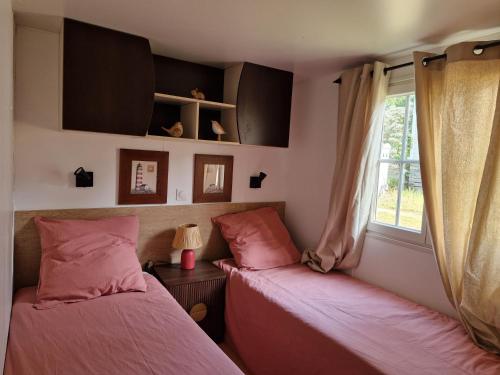 two beds in a room with a window at La Cabane de Nell in Lège-Cap-Ferret