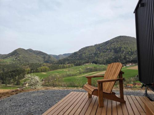 a wooden bench sitting on a deck with mountains in the background at Lahod Tiny House by Tiny Away in Žalec