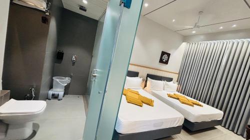 a bedroom with a bed with yellow pillows and a toilet at Balaji Hotel in Somnath
