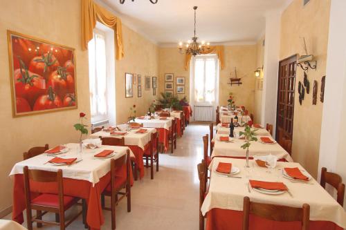 a row of tables in a restaurant with red chairs at Hotel Villa Bianca in Laigueglia