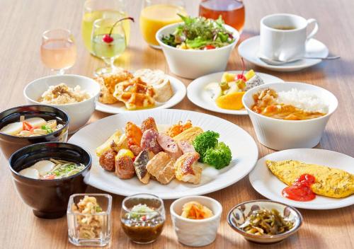 a table with plates of food and bowls of food at HOTEL AlaCOOJU OKINAWA in Urazoe