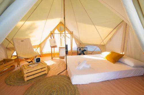 a bedroom in a tent with a bed and a chair at Kampaoh Conil in Conil de la Frontera